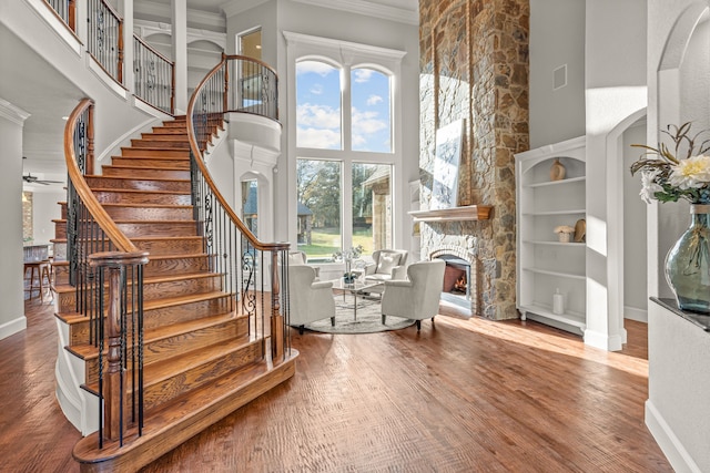 interior space with a fireplace, a high ceiling, hardwood / wood-style flooring, and crown molding