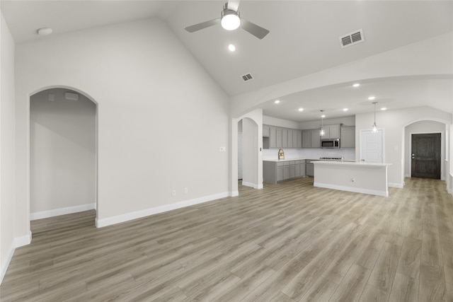 unfurnished living room with ceiling fan, high vaulted ceiling, and light hardwood / wood-style flooring