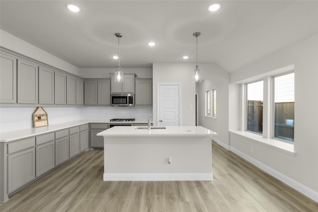 kitchen with light hardwood / wood-style floors, a healthy amount of sunlight, and an island with sink