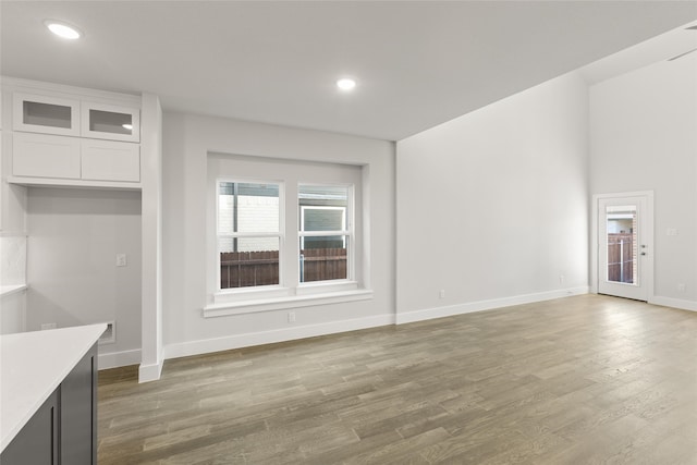 unfurnished living room with baseboards, recessed lighting, and wood finished floors