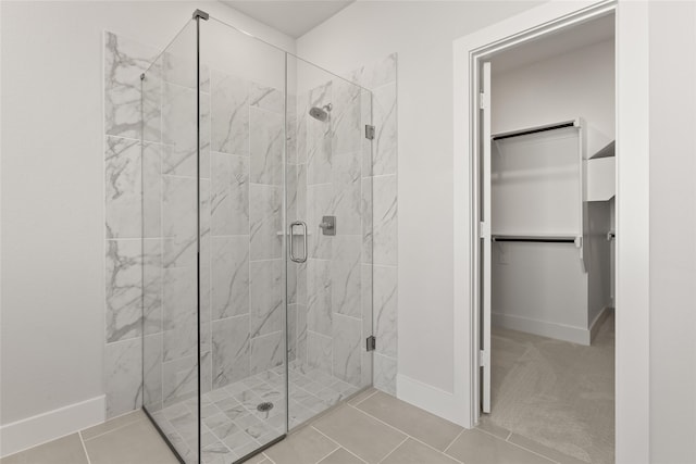 full bathroom with a stall shower, baseboards, tile patterned flooring, and a walk in closet