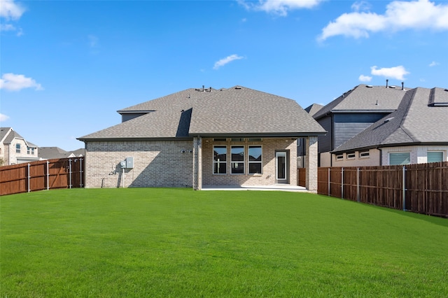 back of house with a yard, brick siding, a patio area, a shingled roof, and a fenced backyard