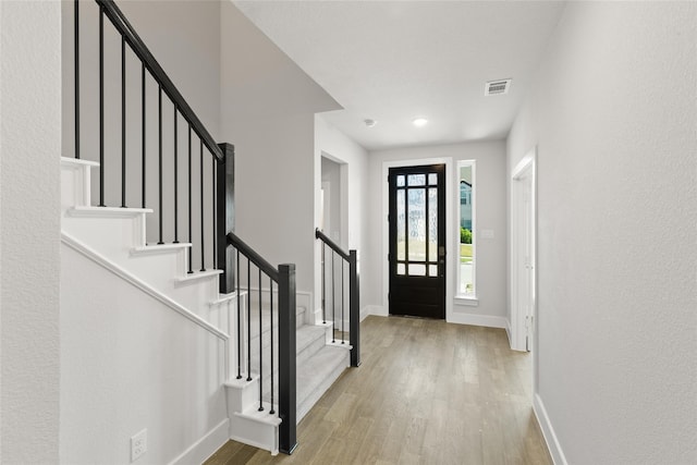 entrance foyer featuring stairway, baseboards, visible vents, and wood finished floors