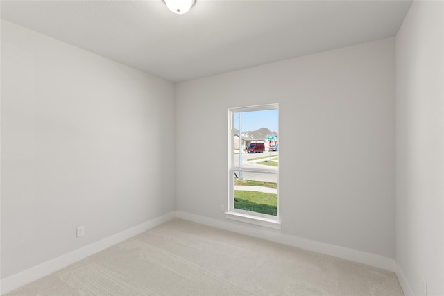 empty room featuring light carpet and baseboards