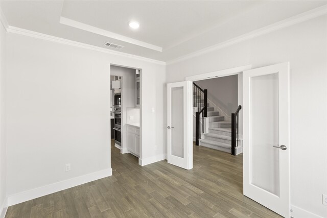 unfurnished room featuring a tray ceiling, visible vents, baseboards, stairway, and dark wood-style floors