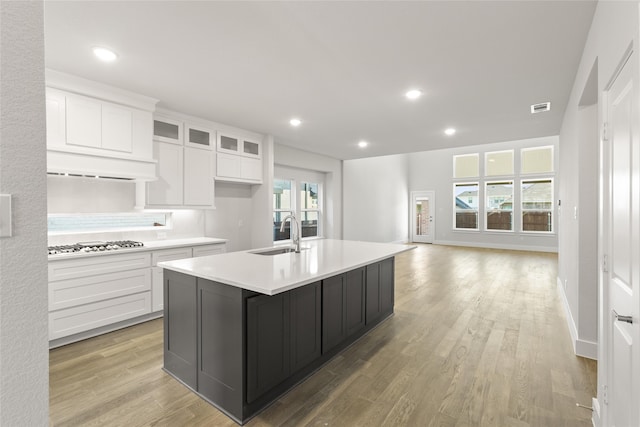 kitchen with light wood finished floors, visible vents, a sink, light countertops, and white cabinets