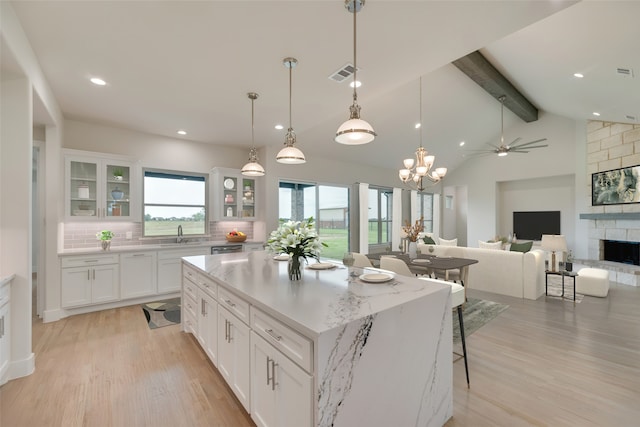 kitchen with beamed ceiling, a center island, white cabinetry, and backsplash