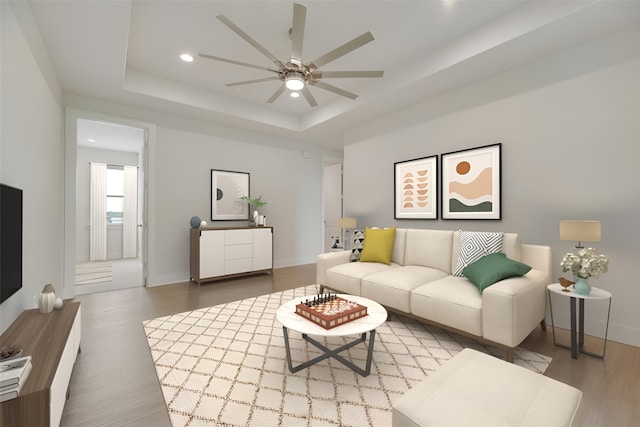 living room with a raised ceiling, ceiling fan, and wood-type flooring