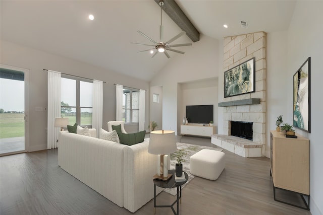 living room with beamed ceiling, wood-type flooring, ceiling fan, and a fireplace