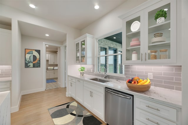 kitchen with decorative backsplash, sink, white cabinets, and stainless steel dishwasher