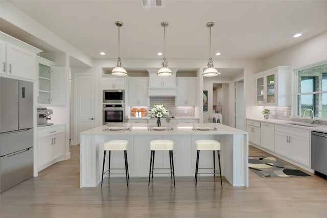 kitchen featuring pendant lighting, an island with sink, white cabinetry, and sink