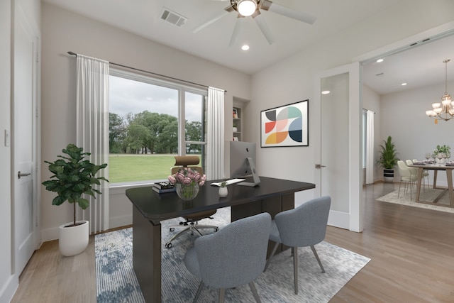 office with ceiling fan with notable chandelier and light hardwood / wood-style flooring