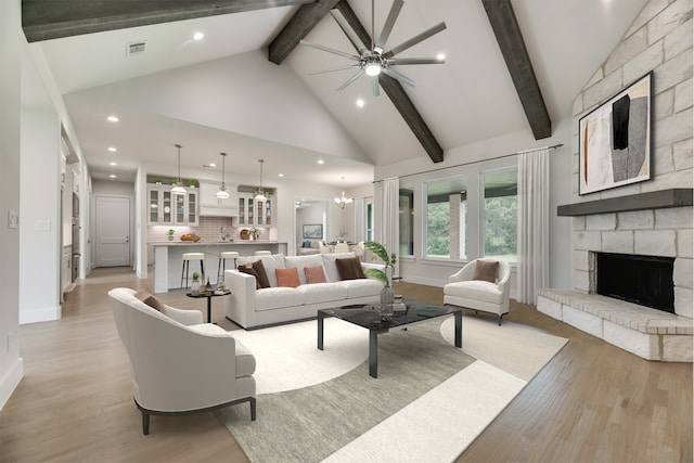 living room featuring high vaulted ceiling, ceiling fan with notable chandelier, light wood-type flooring, a fireplace, and beam ceiling