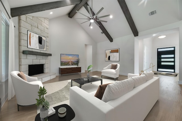 living room featuring high vaulted ceiling, ceiling fan, a fireplace, beamed ceiling, and light hardwood / wood-style floors