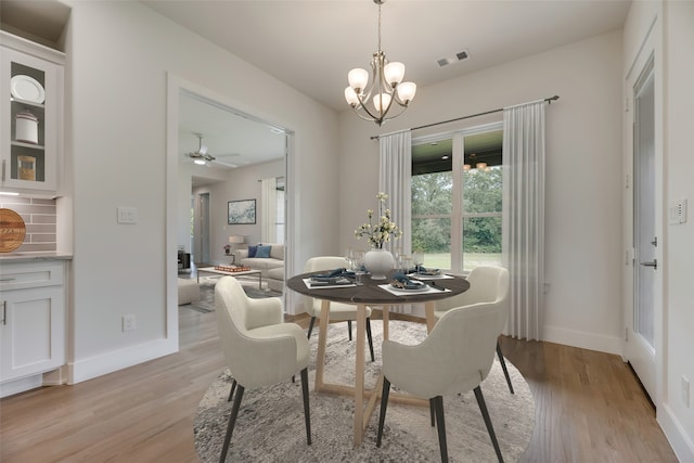 dining room featuring ceiling fan with notable chandelier and light wood-type flooring