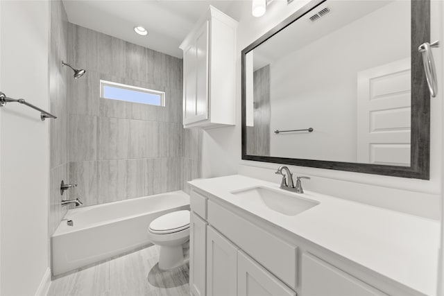 full bathroom featuring tiled shower / bath combo, vanity, and toilet