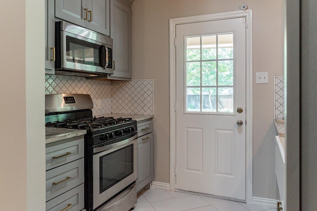 kitchen with stainless steel appliances, gray cabinetry, light tile patterned floors, and decorative backsplash