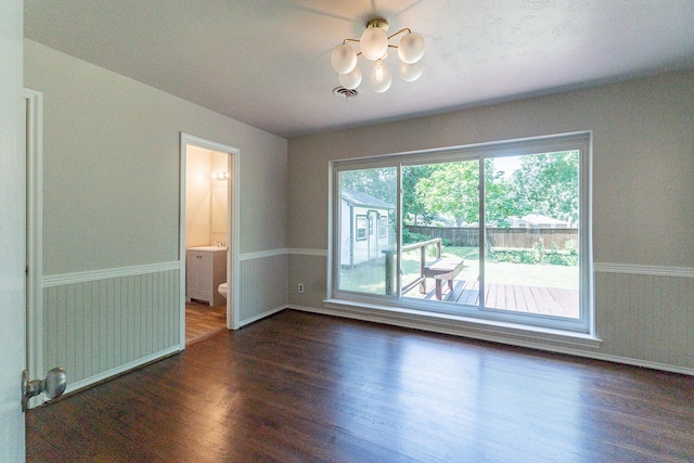 spare room with dark wood-type flooring and a notable chandelier