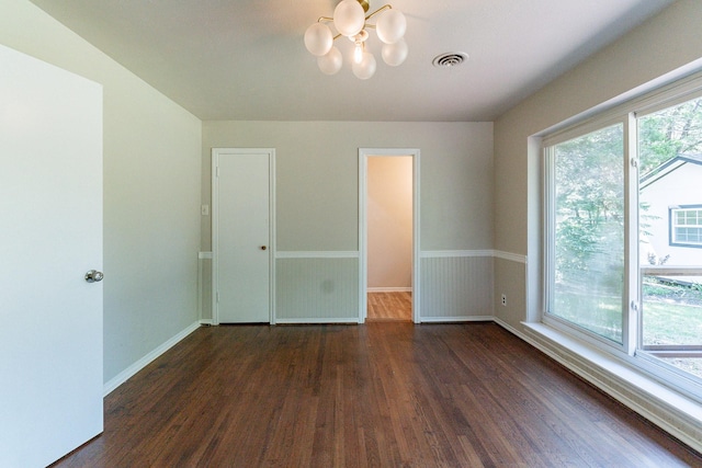 unfurnished room featuring dark hardwood / wood-style flooring and a notable chandelier