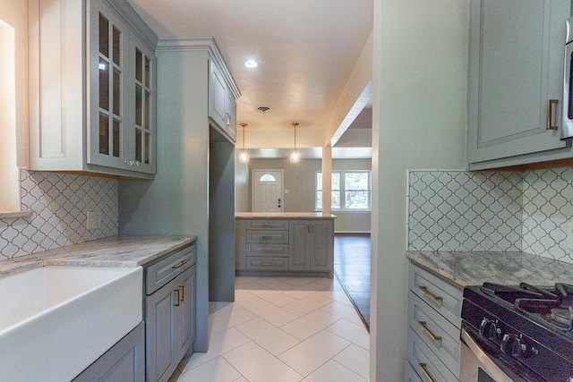 kitchen with hanging light fixtures, light stone countertops, gray cabinets, and tasteful backsplash