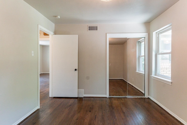 unfurnished bedroom featuring dark hardwood / wood-style floors and a closet