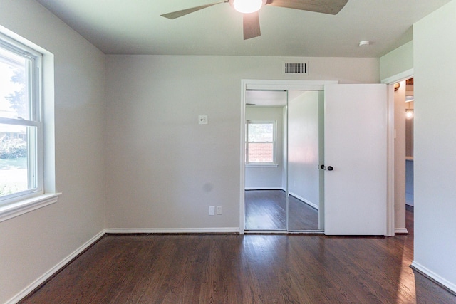 unfurnished bedroom with multiple windows, dark hardwood / wood-style floors, a closet, and ceiling fan