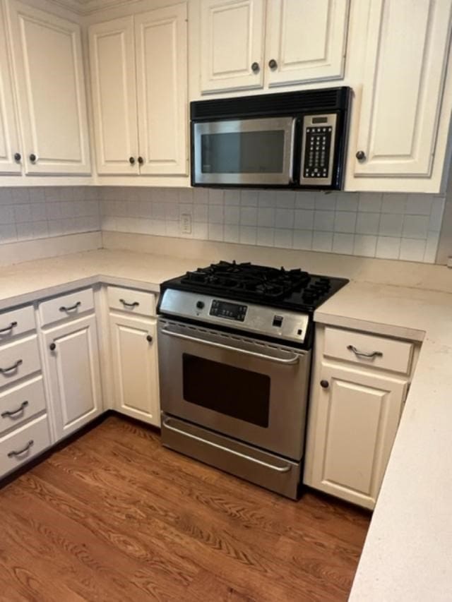 kitchen with stainless steel appliances, white cabinetry, tasteful backsplash, and dark wood-type flooring