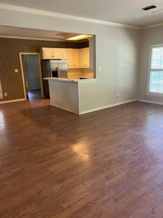 unfurnished living room featuring dark hardwood / wood-style floors and crown molding