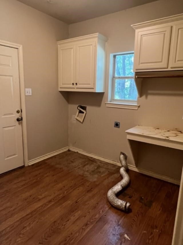 laundry room with electric dryer hookup, dark hardwood / wood-style flooring, and cabinets