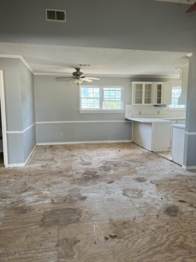 interior space with a textured ceiling, ceiling fan, and crown molding