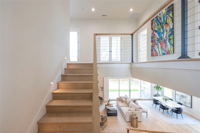 stairway with hardwood / wood-style floors and a towering ceiling