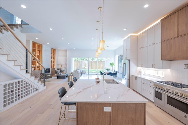 kitchen with a breakfast bar, white cabinetry, premium appliances, hanging light fixtures, and a spacious island