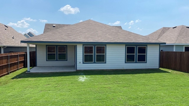 rear view of house with a shingled roof, a lawn, a patio area, and a fenced backyard