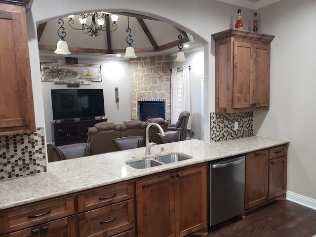 kitchen with pendant lighting, backsplash, sink, stainless steel dishwasher, and a chandelier