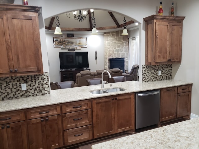 kitchen featuring stainless steel dishwasher, a stone fireplace, sink, and hanging light fixtures