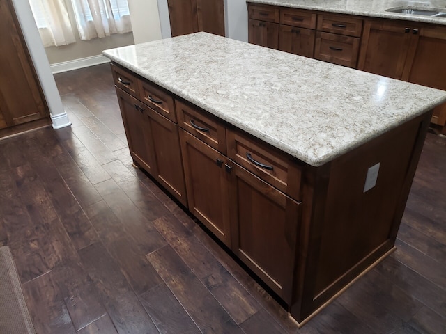 kitchen featuring a center island, dark hardwood / wood-style floors, light stone counters, and sink