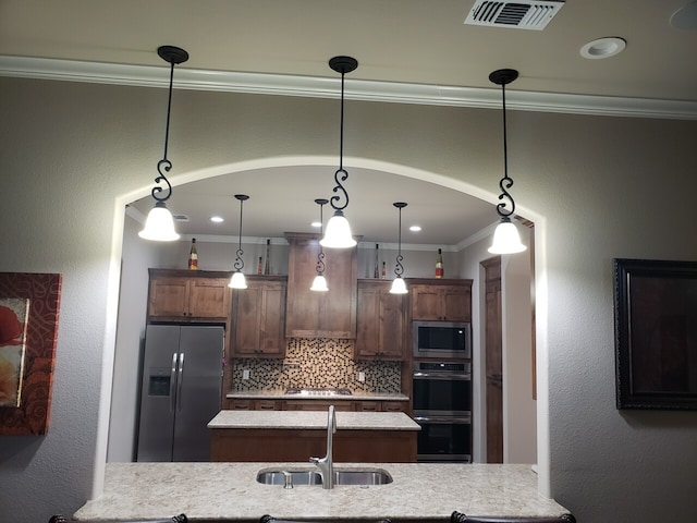 kitchen with sink, crown molding, decorative backsplash, decorative light fixtures, and stainless steel appliances