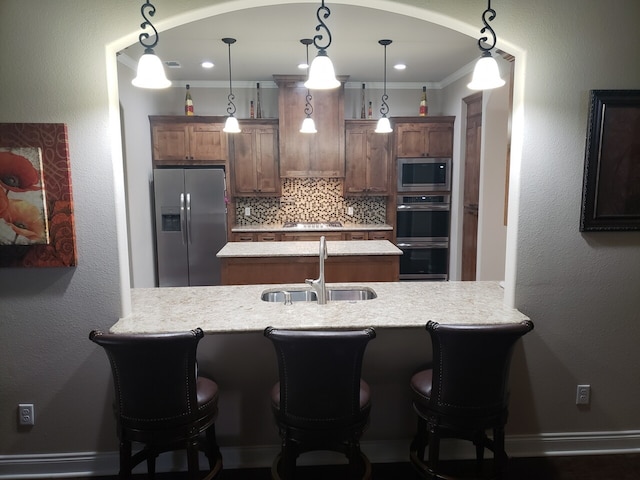 kitchen with pendant lighting, backsplash, sink, ornamental molding, and stainless steel appliances