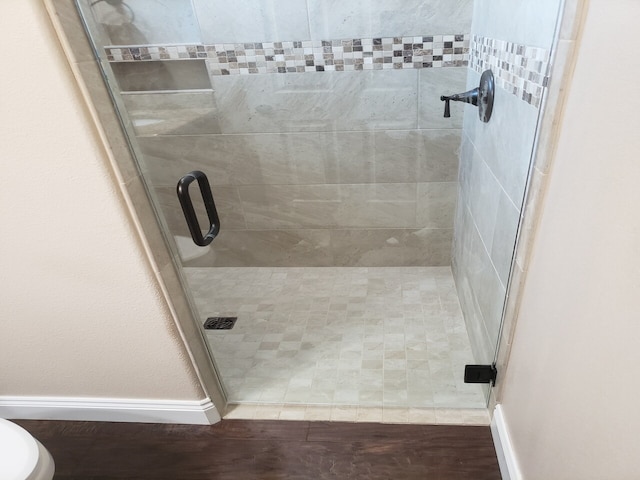 bathroom with hardwood / wood-style flooring and an enclosed shower