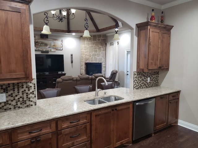 kitchen with sink, tasteful backsplash, a stone fireplace, stainless steel dishwasher, and pendant lighting