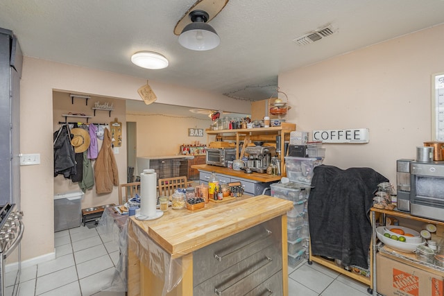 kitchen featuring butcher block countertops, a textured ceiling, light tile patterned flooring, and range