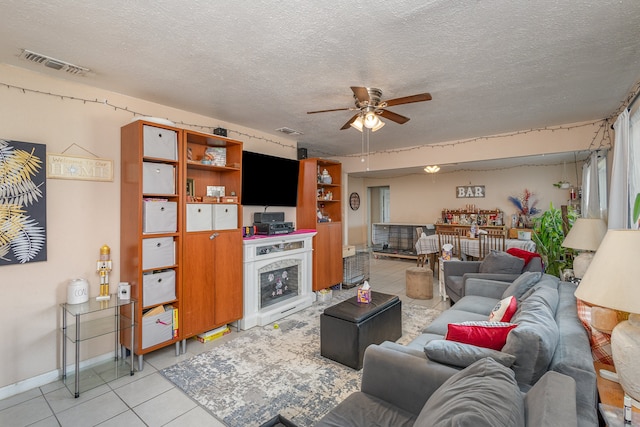 living room featuring a textured ceiling, ceiling fan, and light tile patterned floors