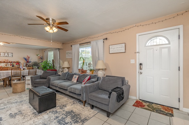 living room featuring a textured ceiling, tile patterned floors, and ceiling fan