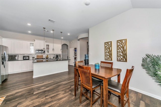 dining space with dark hardwood / wood-style flooring, sink, and lofted ceiling