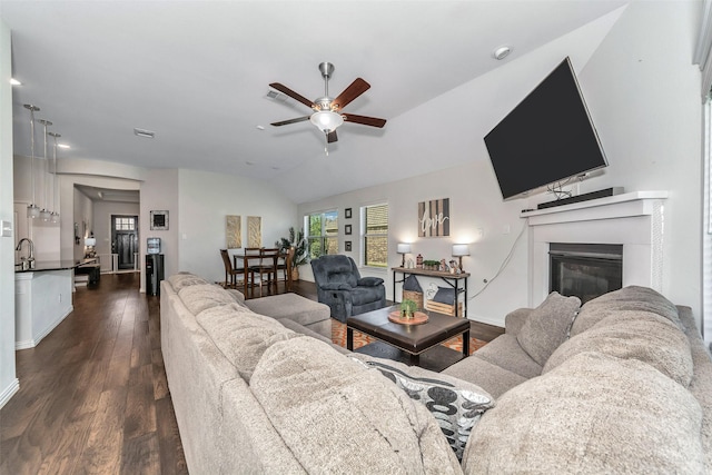 living room with lofted ceiling, dark wood-type flooring, sink, and ceiling fan