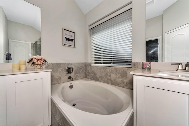 bathroom with vanity and tiled tub