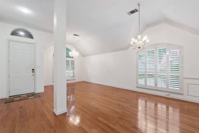 entryway with ornamental molding, wood-type flooring, vaulted ceiling, and a notable chandelier