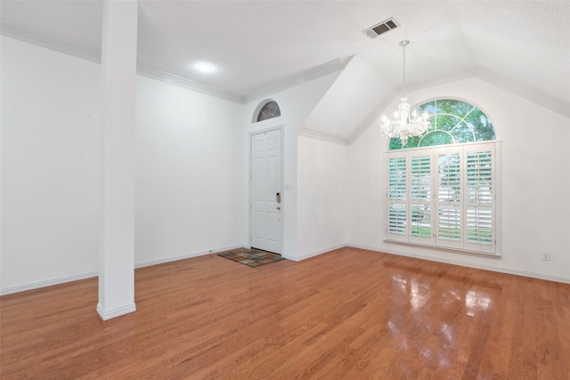 empty room featuring hardwood / wood-style flooring, lofted ceiling, and an inviting chandelier