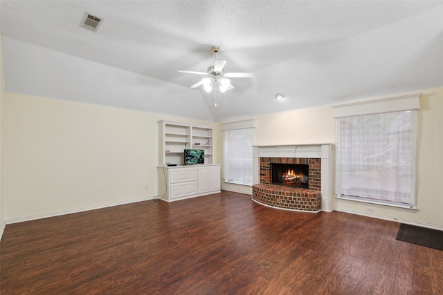 unfurnished living room with lofted ceiling, dark wood-type flooring, a brick fireplace, ceiling fan, and a textured ceiling