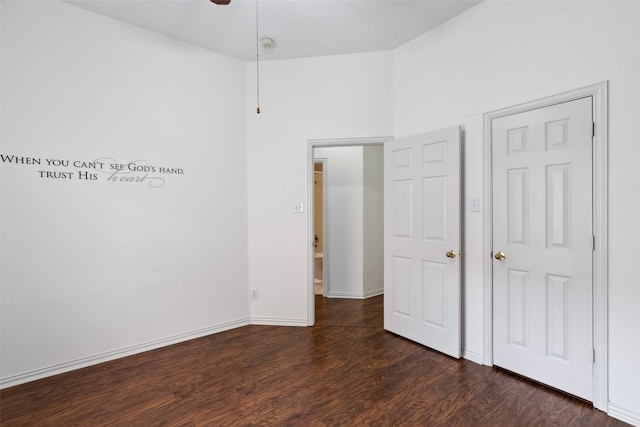 unfurnished bedroom with ceiling fan, dark hardwood / wood-style flooring, and a towering ceiling